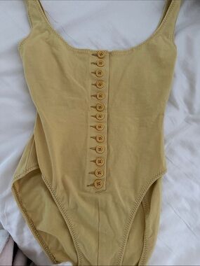Norma Kamali , bodysuit Button-Front One-Piece in Mustard Yellow